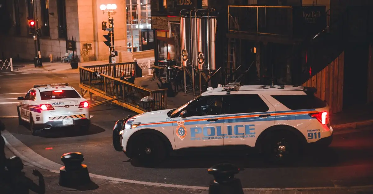 Two police cars on a city street at night