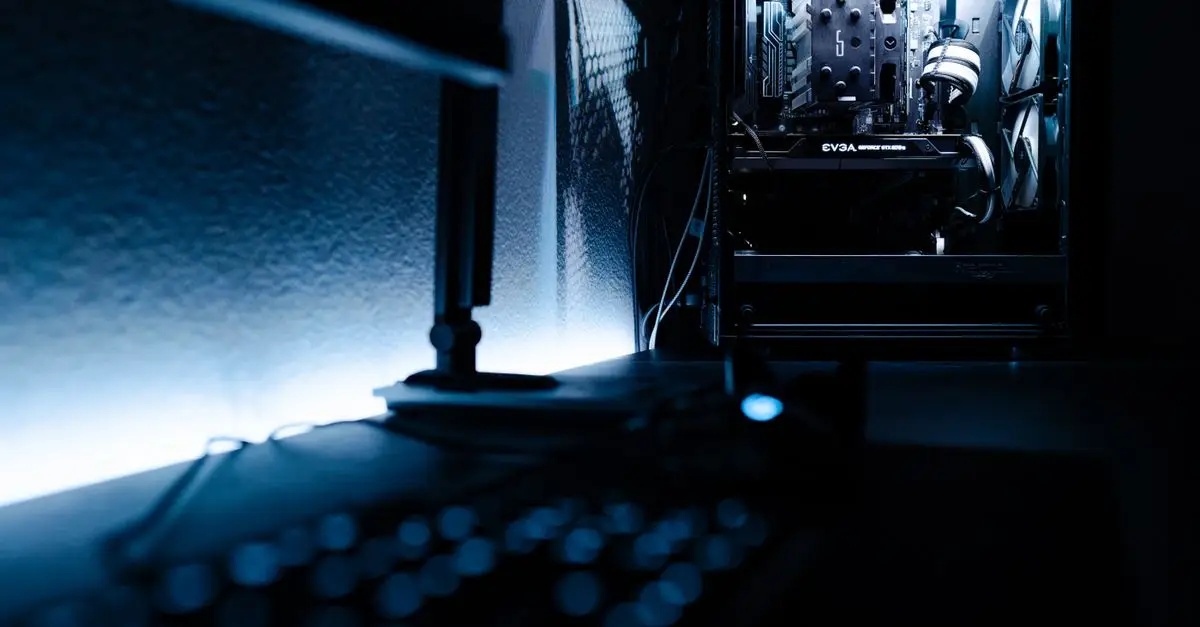 Close-up of a gaming PC case and keyboard lit by a monitor