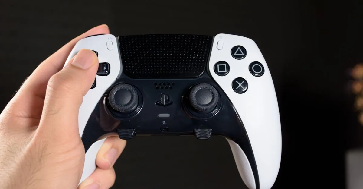Close-up of a hand holding a modern gaming controller against a dark background.